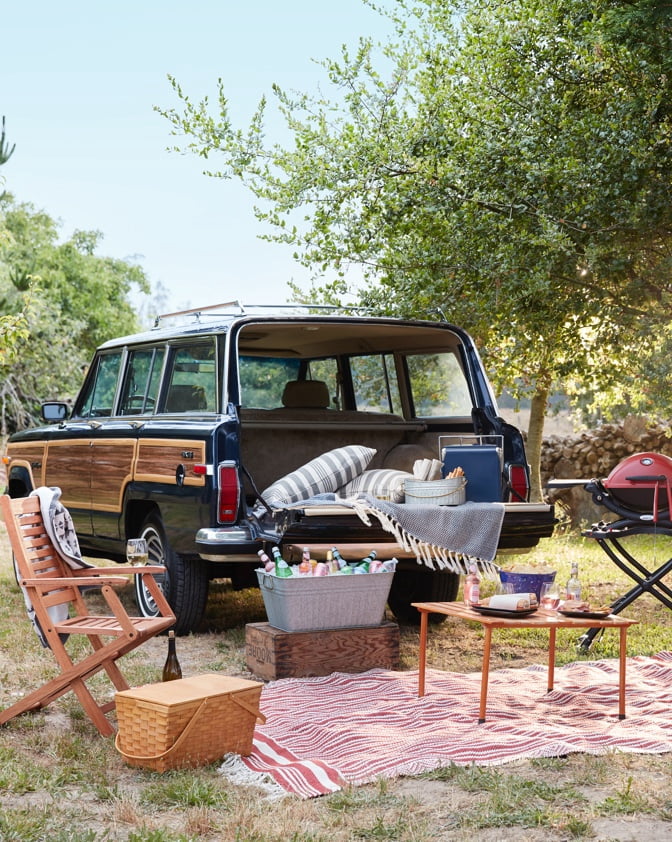 A vintage-style Volkswagon with a tailgating set up including stylish folding chairs, portable grills, and cozy outdoor decor form dxoffersmall.com