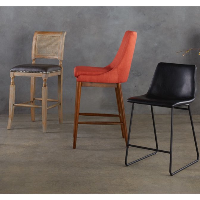Three bar stools in different styles against a trendy concrete background as the intro to our barstool buying guide.